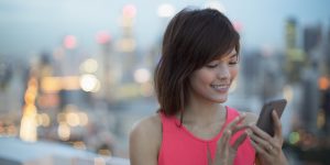 Woman using handphone with city in background