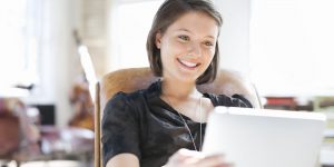 Young woman relaxing in chair using digital tablet